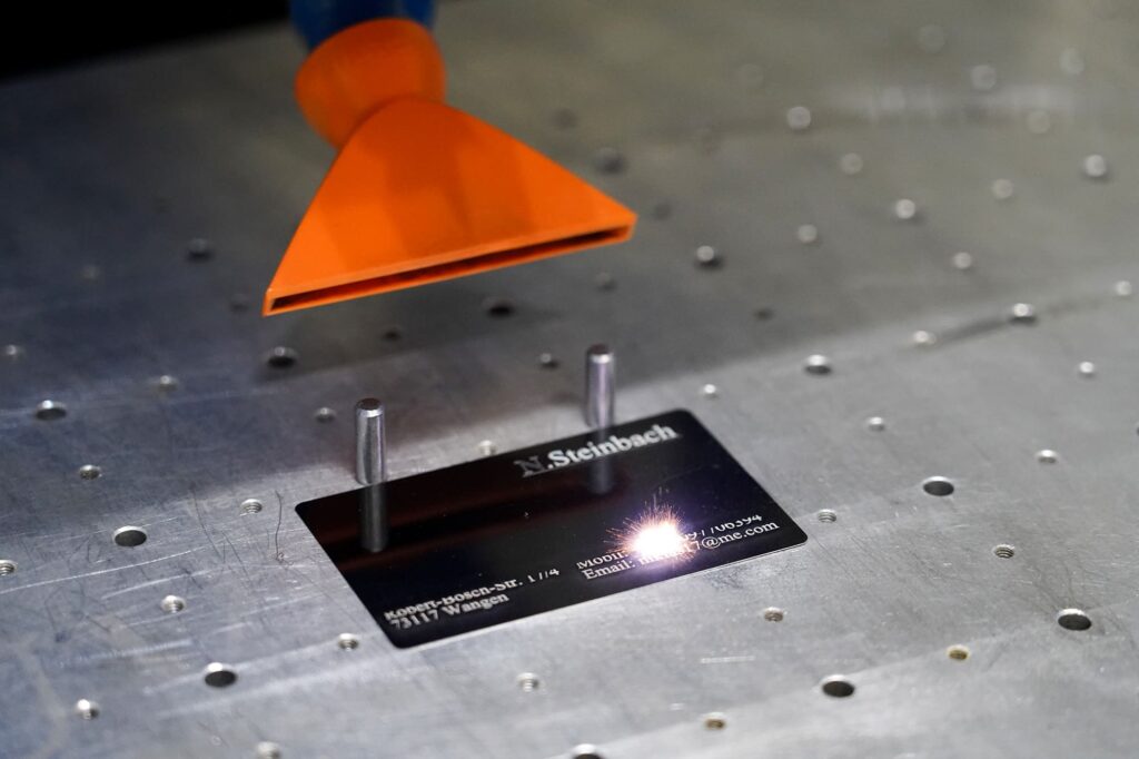 Schwarze Visitenkarte mit Kontaktdaten von Niklas Steinbach wird mit Lasergravur bearbeitet